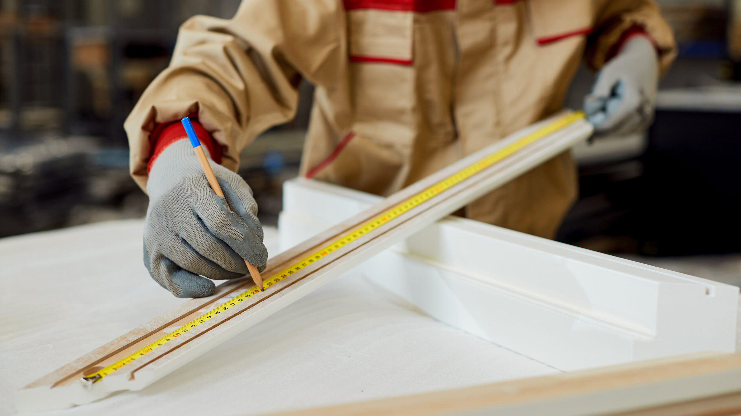 Close-up of manual worker marking measurements on a piece of woo