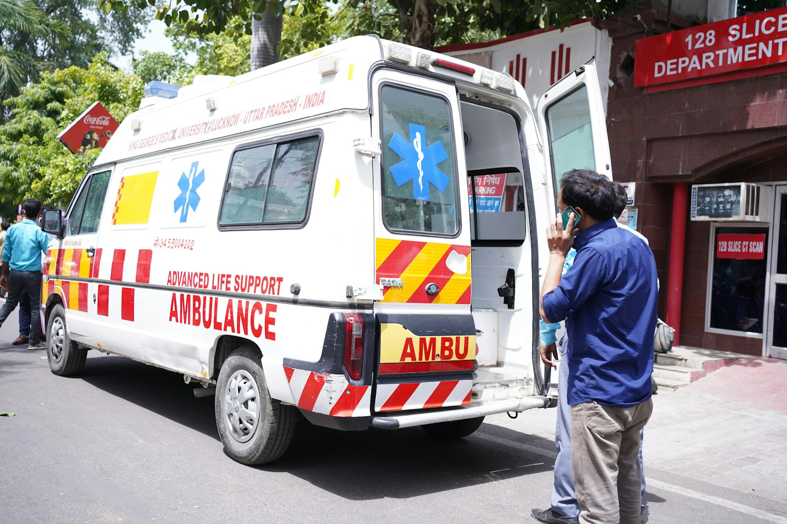 Photo by Aman Chaturvedi a man standing next to an ambulance parked on the side of a road